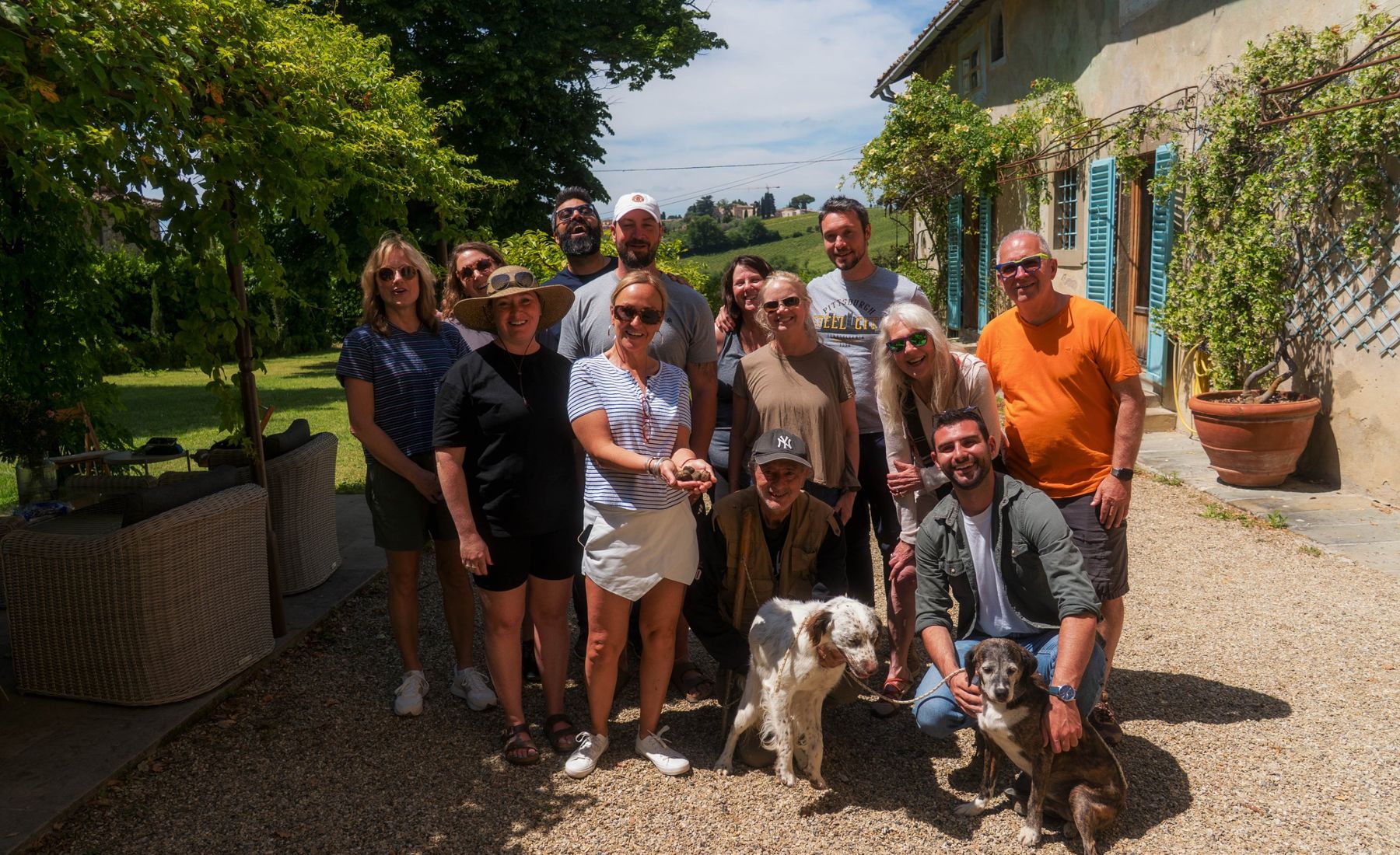 A smiling group outside a Tuscan villa with the truffle hunters, holding the morning's truffles