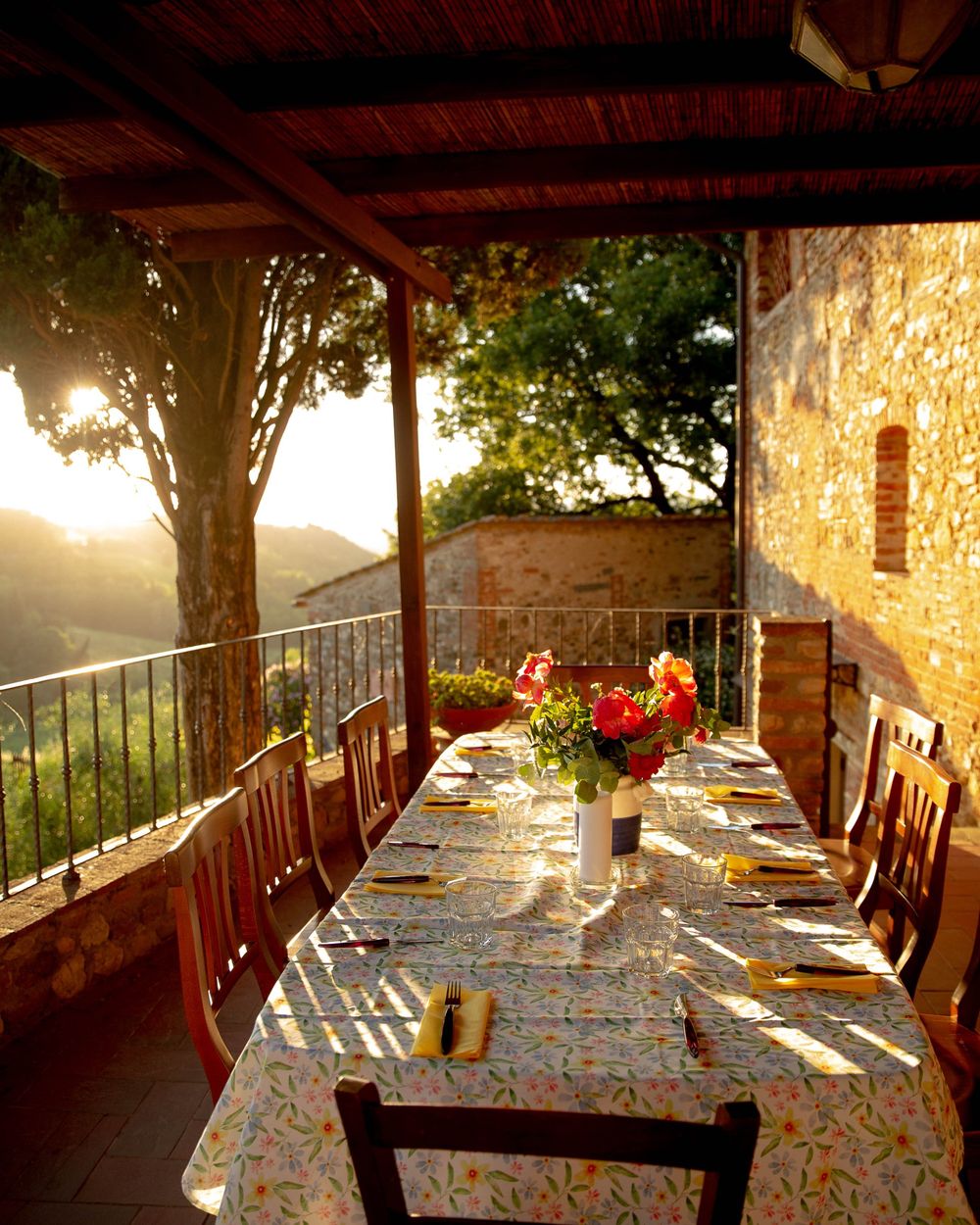 A long table set for dinner under a pergola at sunset, overlooking the hills