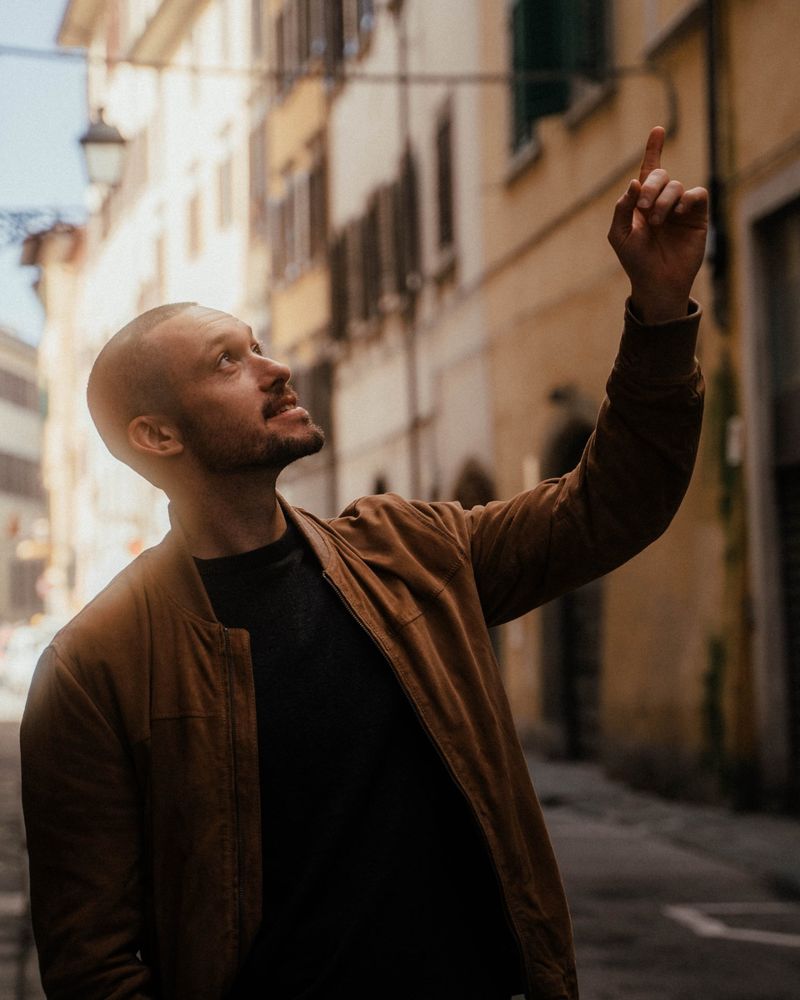 Tom Scharre in a narrow Florence street, smiling and pointing up at the buildings